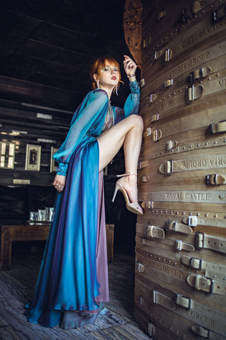 Blue chiffon gown with deep V neckline, long sheer sleeves, and high slit.