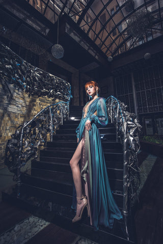 Blue chiffon gown with deep V neckline, long sheer sleeves, and high slit.