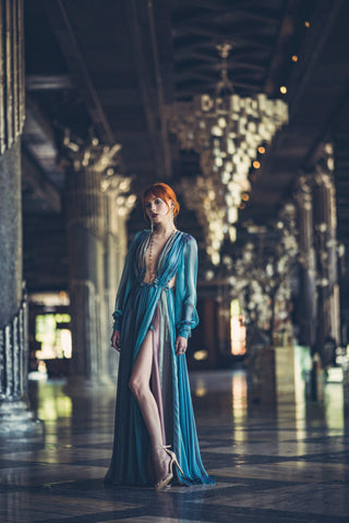 Blue chiffon gown with deep V neckline, long sheer sleeves, and high slit.