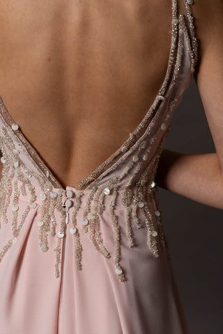 Blush pink evening gown with V-neckline, beaded bodice, open back and flowing A-line skirt.