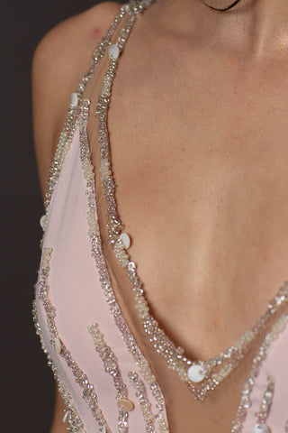 Blush pink evening gown with V-neckline, beaded bodice, open back and flowing A-line skirt.